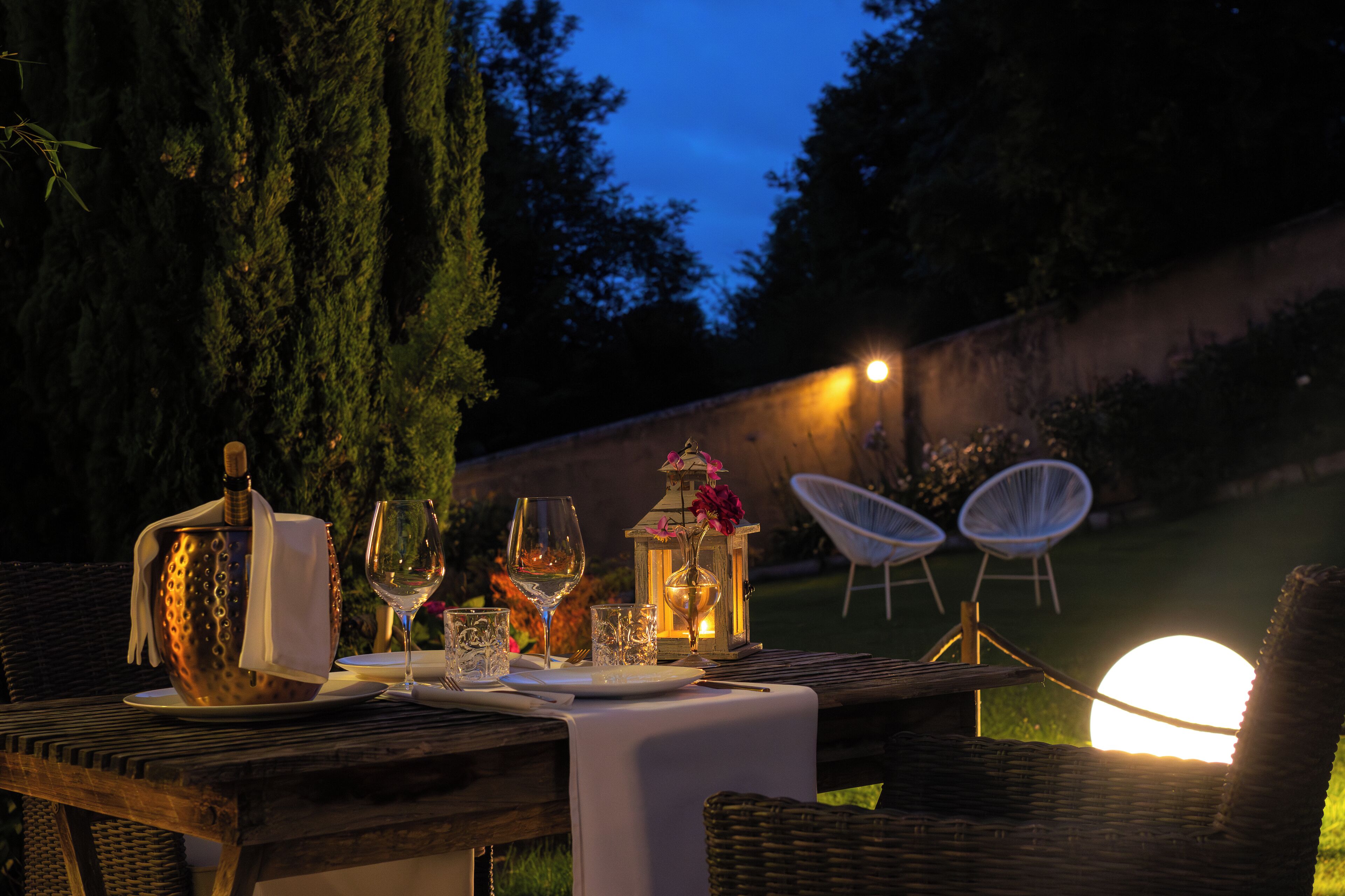 An outdoor dining setup with a table, chairs, and a lantern.