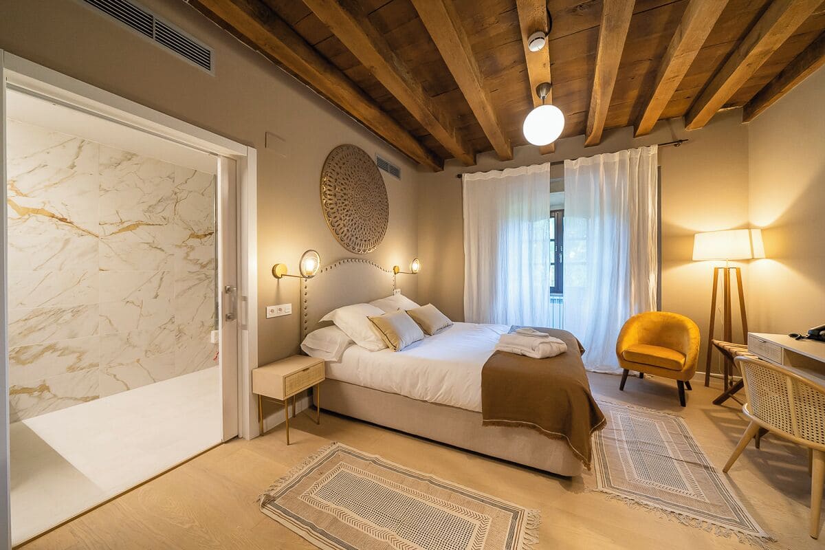 Une chambre à coucher avec un lit, des lampes de chevet, une chaise et un bureau.