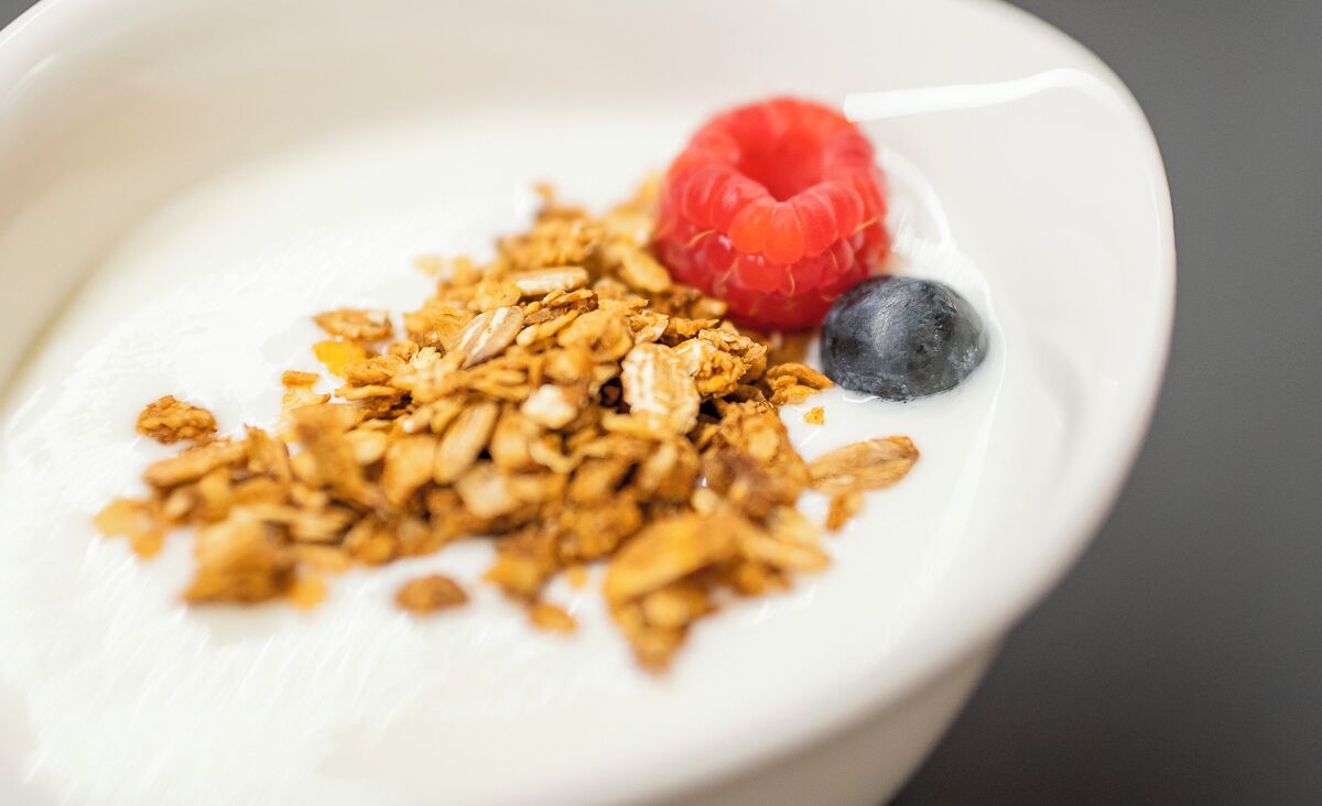 Een kom yoghurt met granola en bessen.