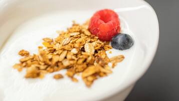 Een kom yoghurt met granola en bessen.
