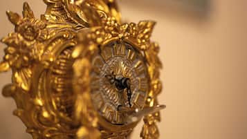Un primer plano de un reloj dorado ornamentado con detalles intrincados y esfera con números romanos.