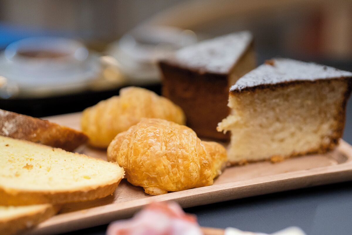 Une variété de viennoiseries présentées sur une planche en bois, notamment un croissant, une part de gâteau et une pâtisserie ronde.