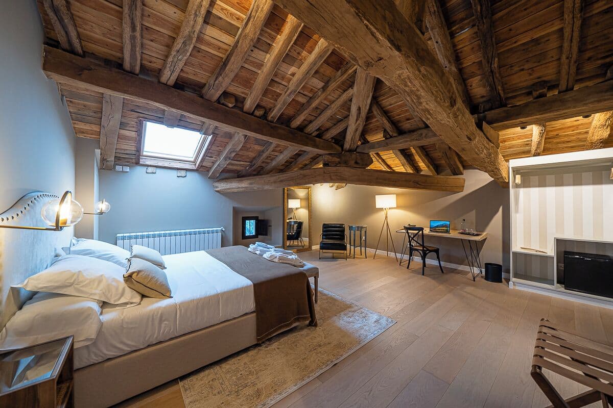 Une chambre à coucher avec un grand lit, un bureau, une chaise et une cheminée.