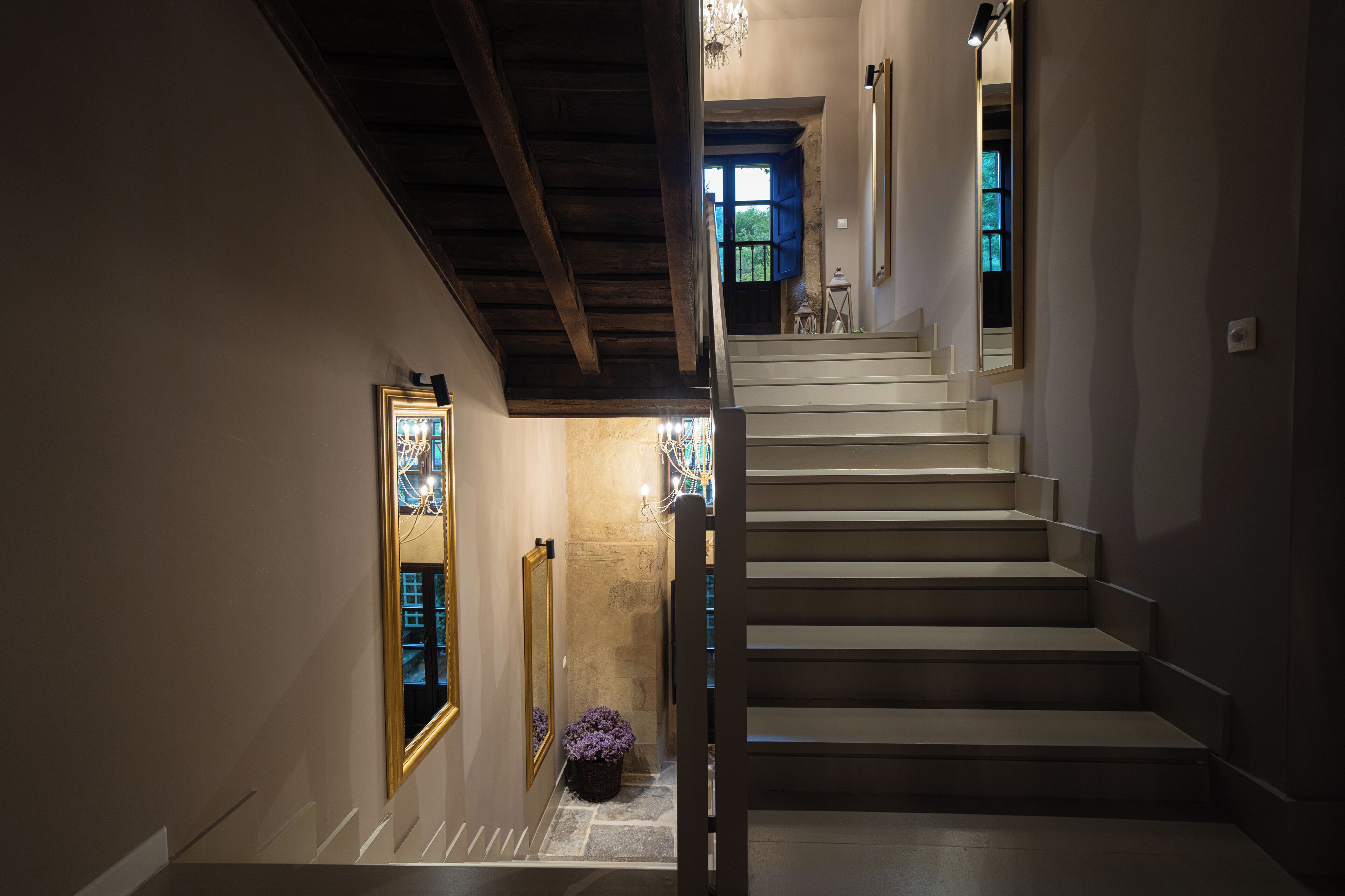 A staircase with a wooden ceiling and a view of a room with a window.