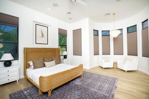 A bedroom with a large bed, bedside tables, a nightstand, a chair, and a window with blinds. - Mesa Luxury Home | Sleeps 14 | Heated Spa + Game Garage (Mesa)