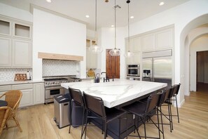 A modern kitchen with a large island, stainless steel appliances, and pendant lighting.