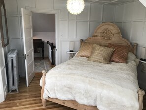 A bedroom with a wooden bed, white bedding, and a decorative headboard.