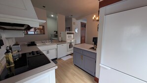 Une cuisine avec des meubles blancs, une cuisinière, un four à micro-ondes et un réfrigérateur.