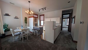 Une cuisine moderne avec des meubles blancs, un îlot central et un coin repas comprenant une table et des chaises.