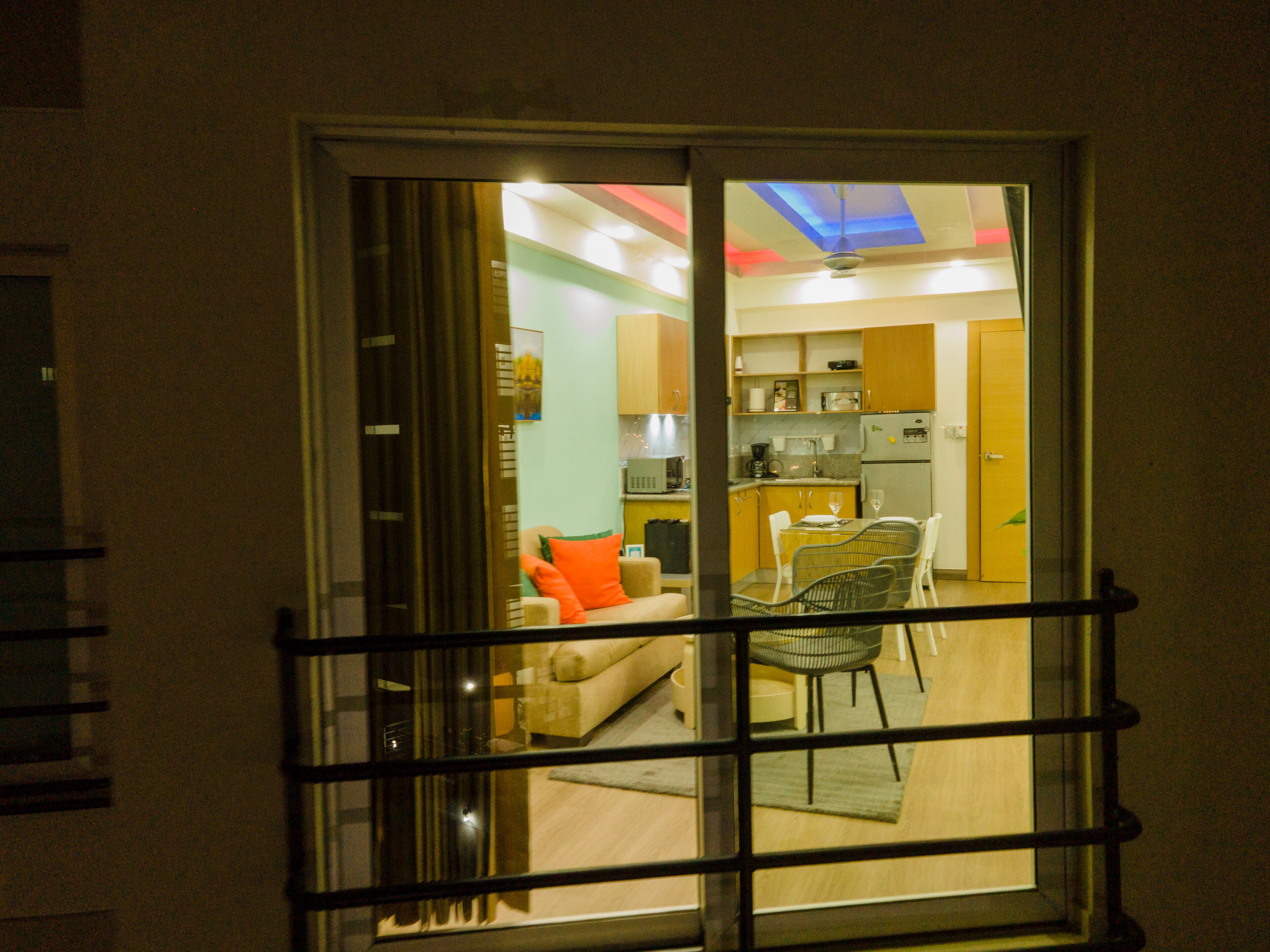 Un interior moderno con sala de estar, cocina y comedor visibles a través de un puerta de cristal.