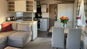 A compact living space with a kitchenette, a dining area, and a seating area with a sofa and chairs. - Arum dog friendly caravan on Rockley Park, Poole (Poole)