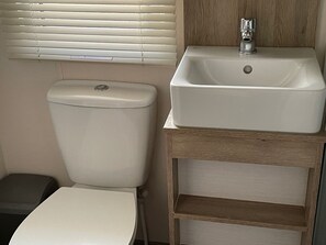 Un bagno compatto con il water, un lavandino e una piccola unità contenitore.