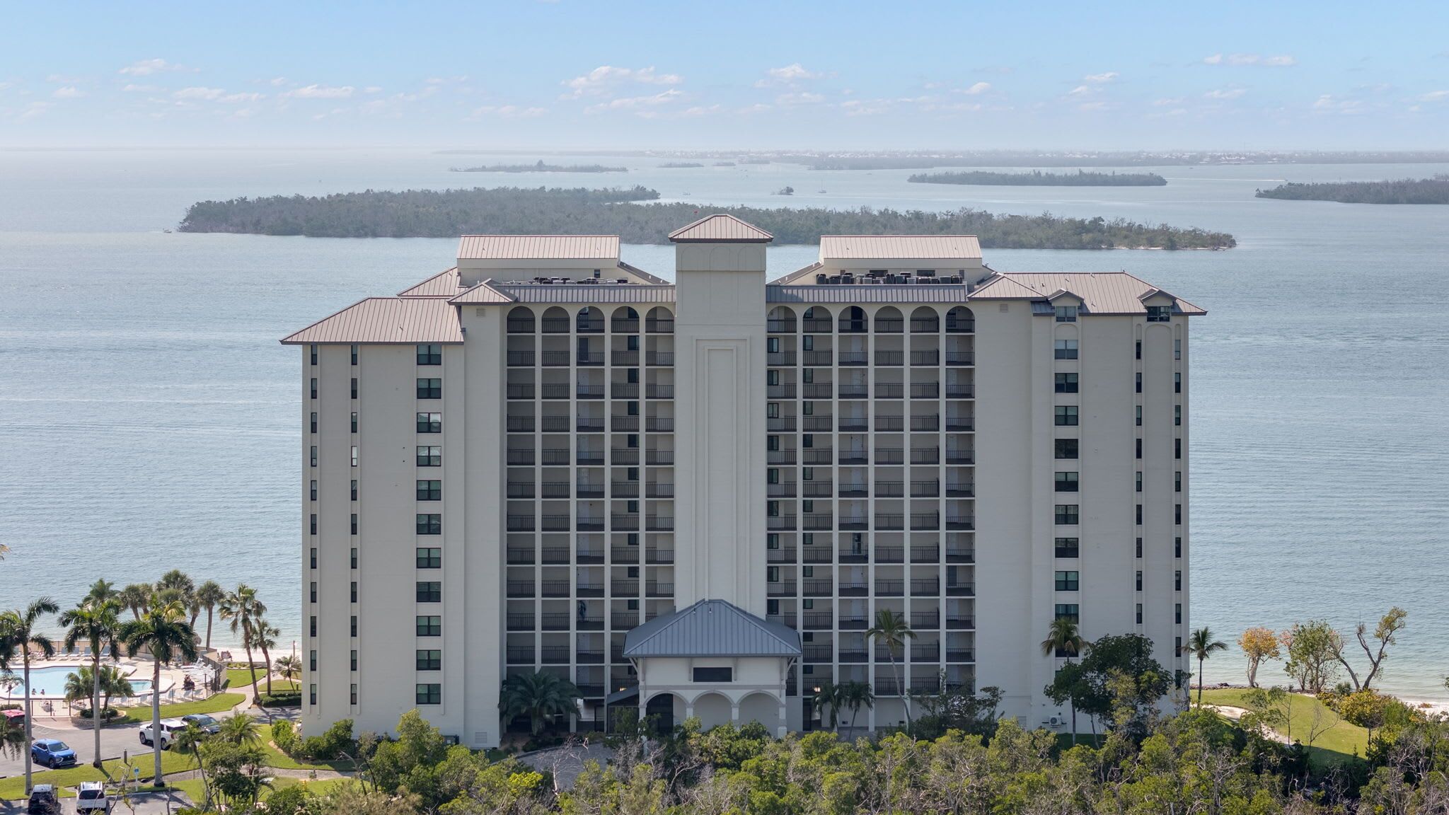A high-rise hotel with multiple balconies, a pool area, and a view of the water.
