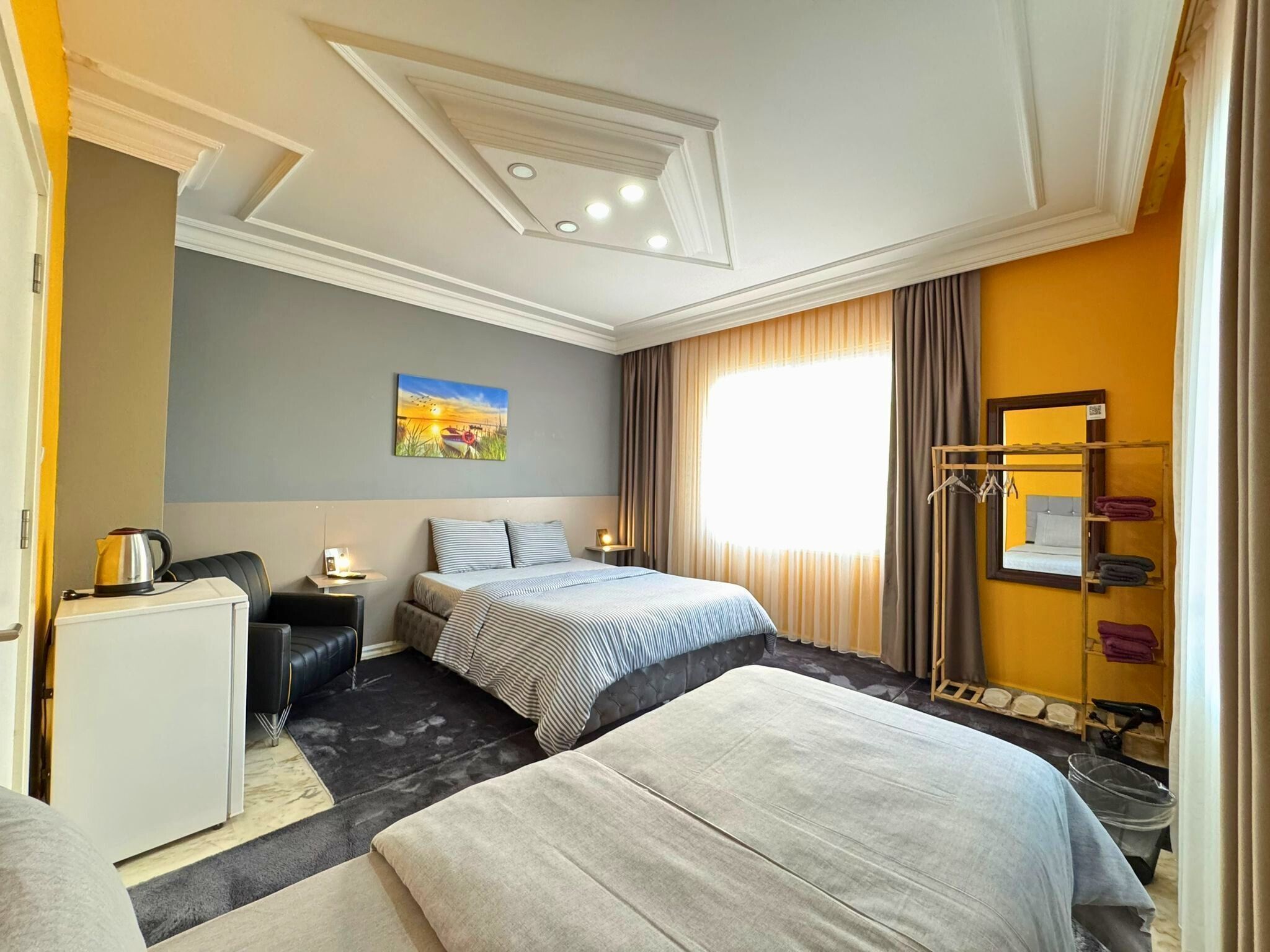 Una habitación de hotel con dos camas, un escritorio, una silla, un armario y un cuadro en la pared.