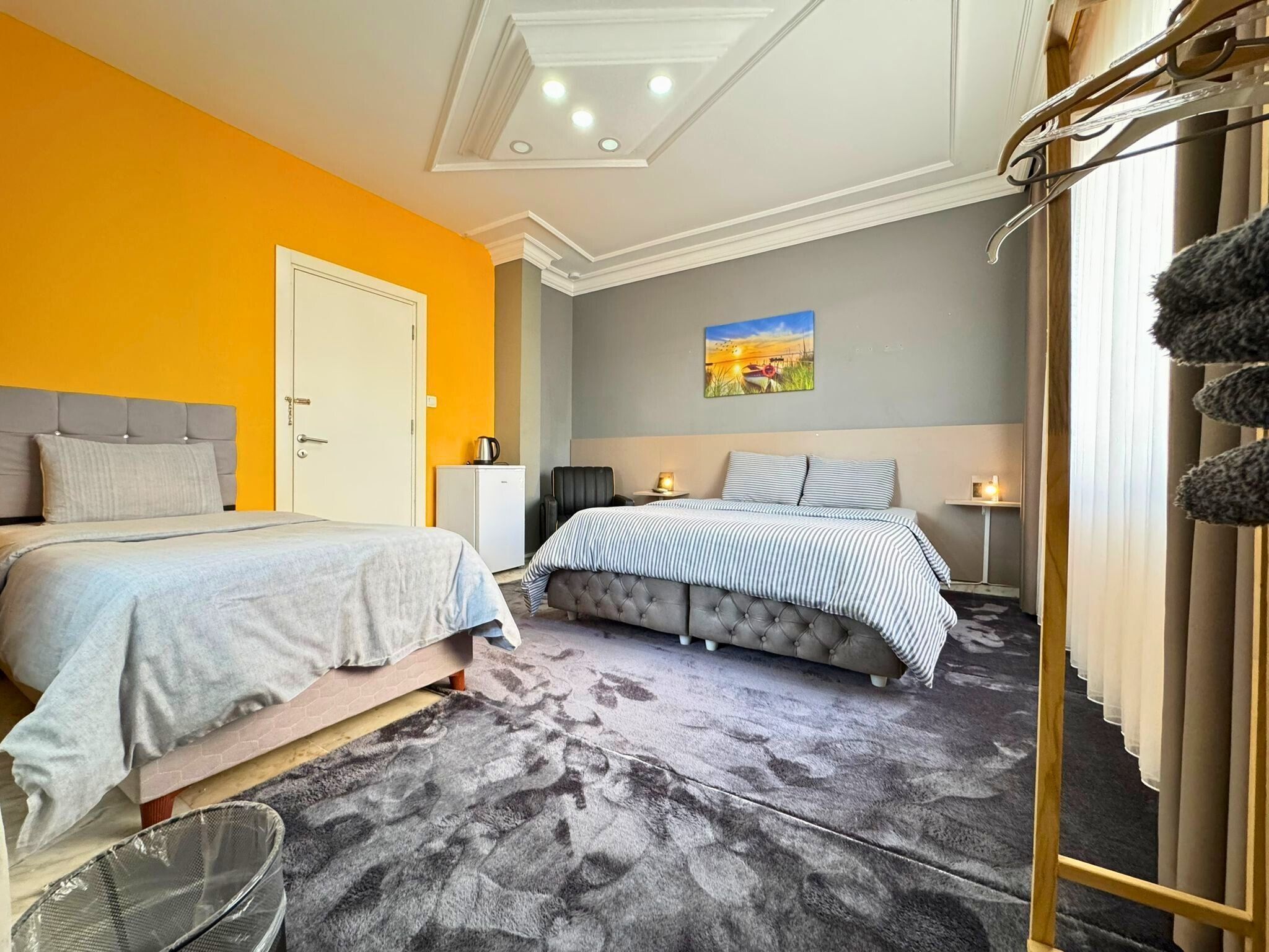 Un dormitorio con dos camas, un mueble pequeño, una silla y un cuadro en la pared.