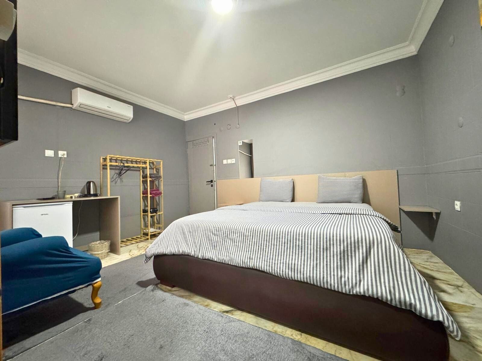 Un dormitorio con una cama grande, un escritorio, un armario y un equipo de aire acondicionado.