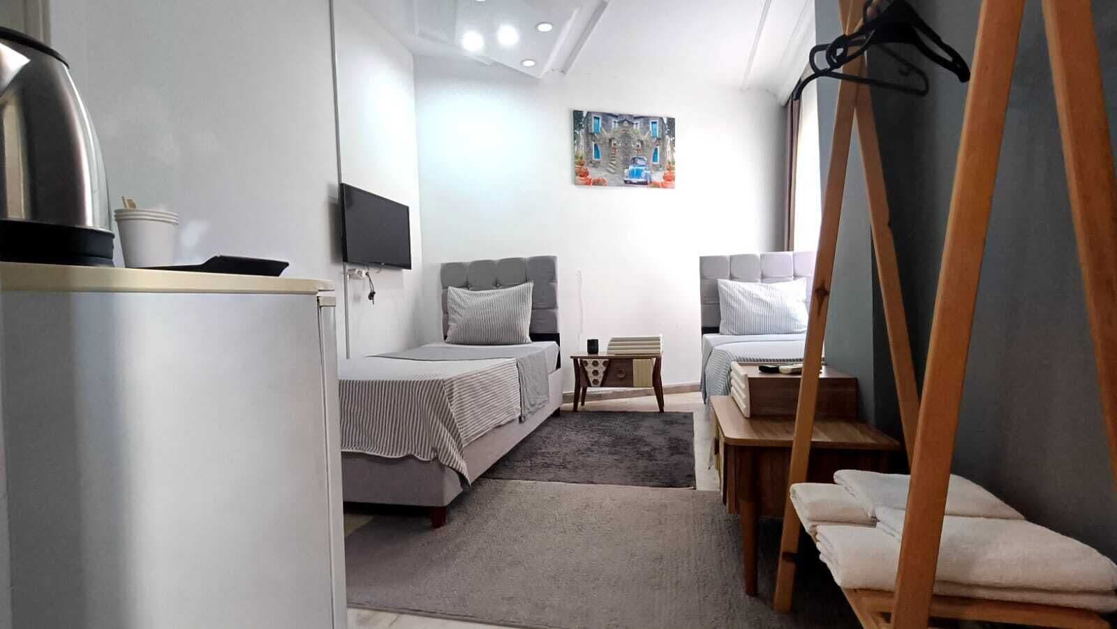 Habitación de hotel pequeña con cama, escritorio, silla, televisor y un cuadro en la pared.