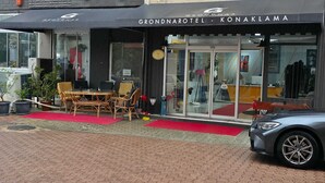 The exterior of the Grand Narotel - Konaklama hotel with outdoor seating and a BMW parked in front. - Grond Konaklama Mersin (Mersin)