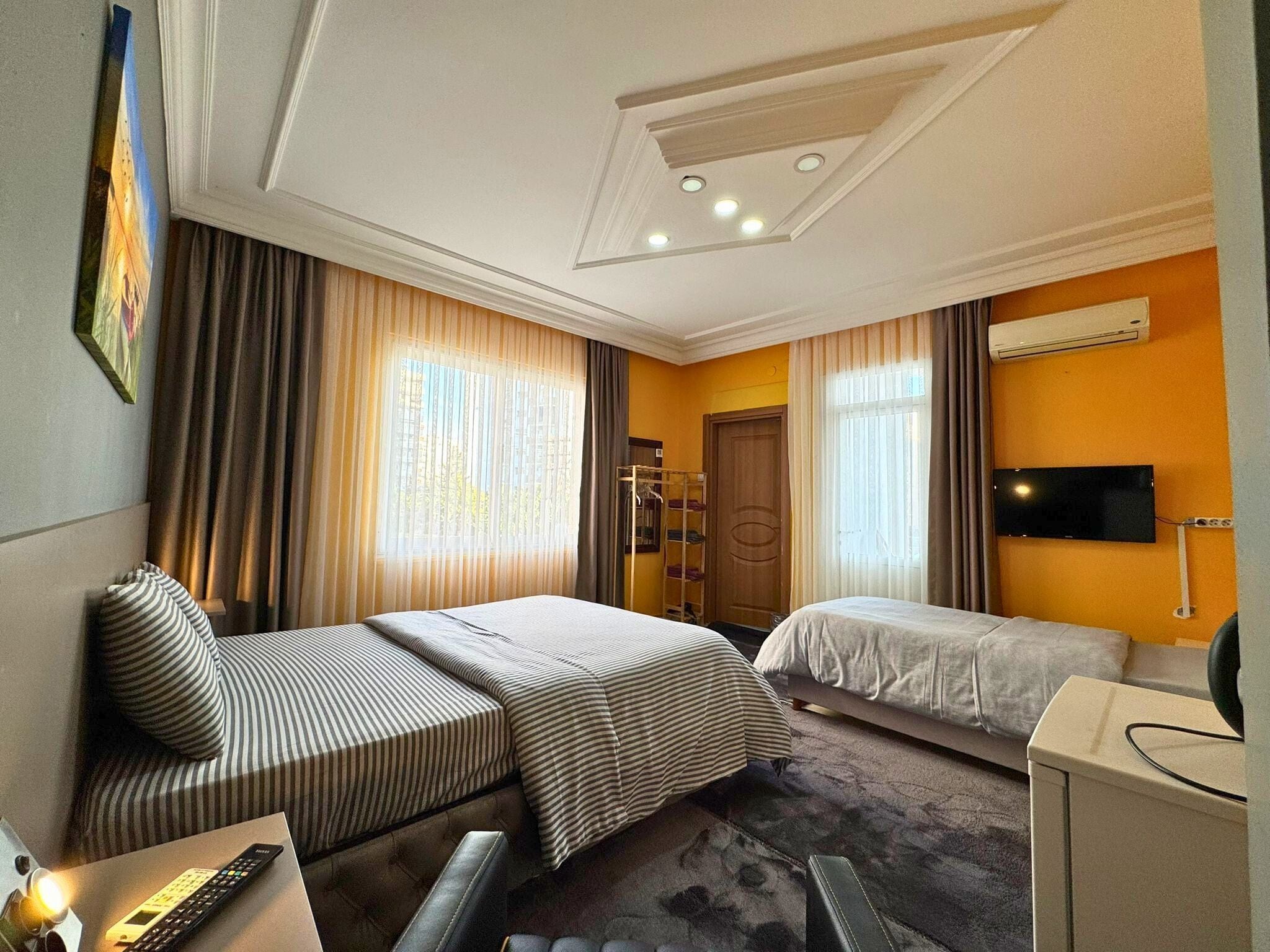 A hotel room with two beds, a desk, a TV, and a wardrobe.