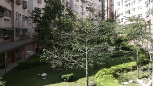 Un quartier résidentiel composé d’immeubles d’habitation à plusieurs étages, d’un petit arbre, ainsi que de pelouses et d’arbustes bien entretenus.