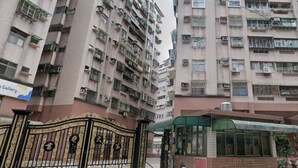Un immeuble résidentiel à plusieurs étages, doté de balcons, d’une entrée sécurisée et d’un abri pour l’arrêt de bus.