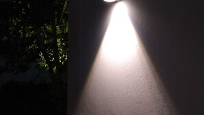 Un luminaire fixé au mur projetant une ombre sur le mur.