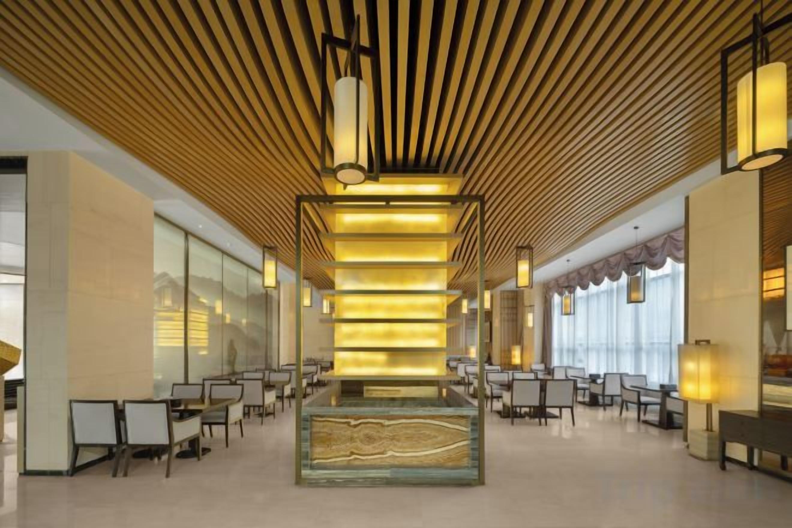 A spacious lobby with a central column, seating arrangements, and a modern ceiling design.