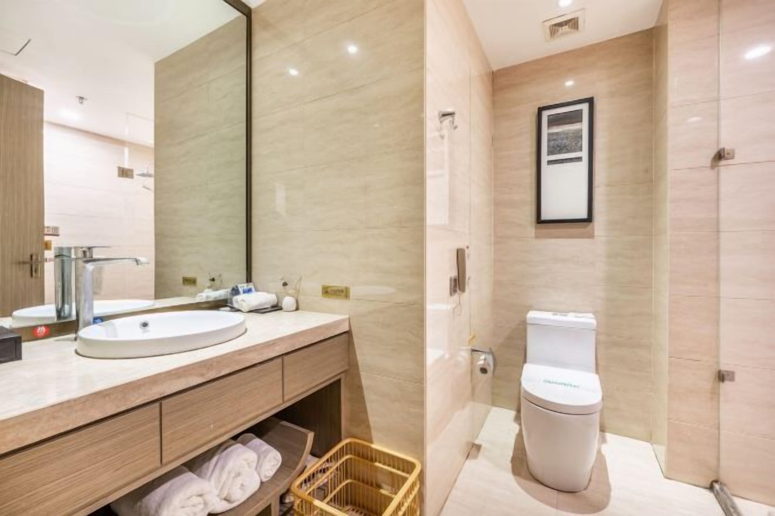 A modern bathroom with a large mirror, a sink, a toilet, and a shower area.
