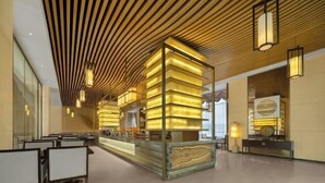 Un moderno vestíbulo de hotel con un mostrador de recepción central, zona de estar y un diseño de techo único.