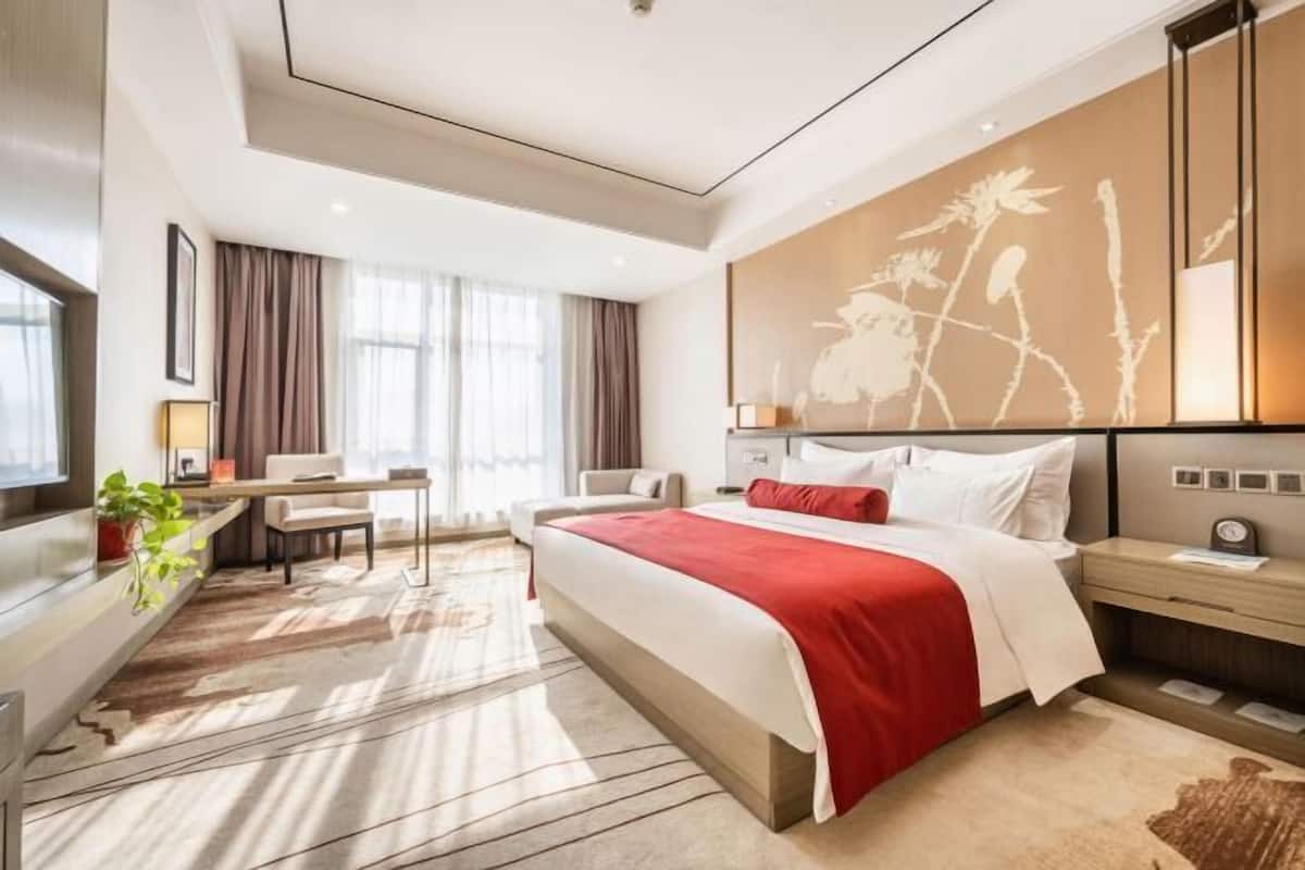 Una habitación de hotel moderna con una cama grande, un escritorio y una zona de estar.