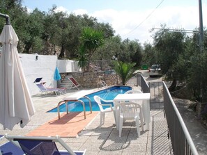 Un espace piscine équipé d’un plongeoir, de chaises longues et d’une table.