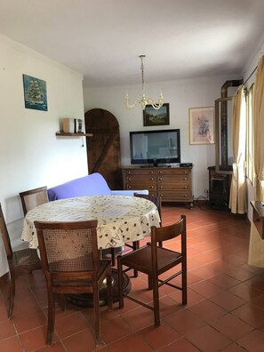 Une pièce confortable avec une table à manger, des chaises, un lit, un téléviseur et une cheminée.