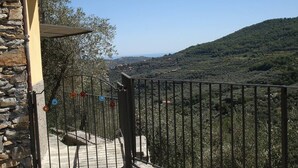 A balcony with a stone wall, metal railing, and a view of a hilly landscape. - Four - Miguel Apartment with panoramic view, among olive trees, sea 15 km away (Villa Viani)