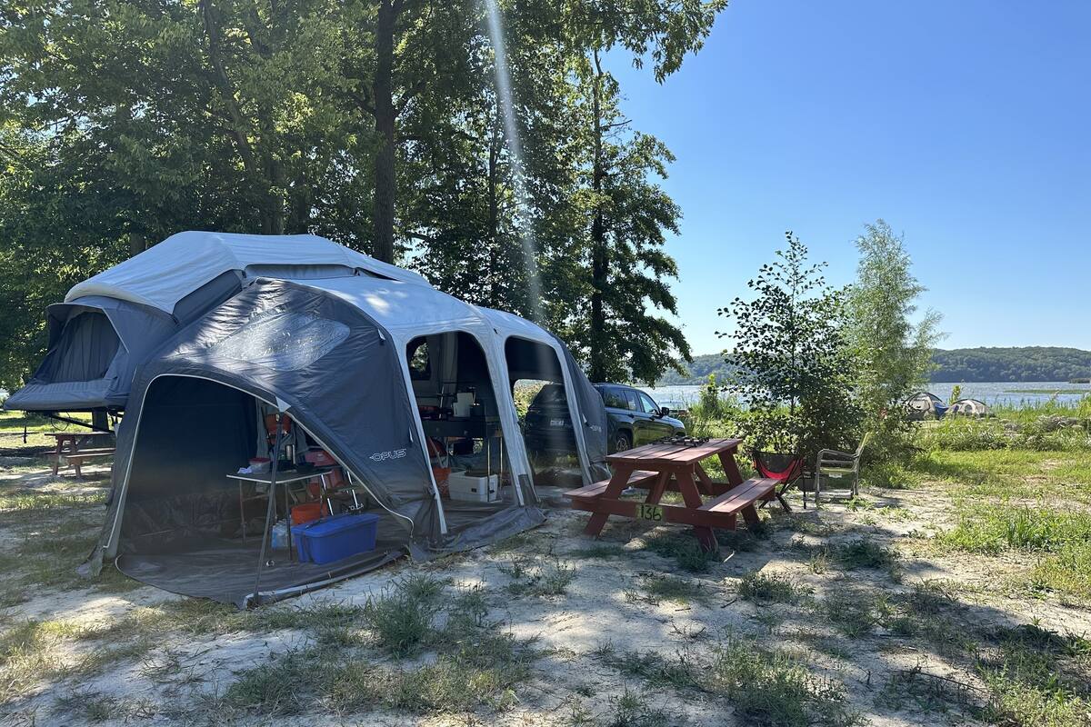 A camping site with a tent, picnic table, and a view of a lake.