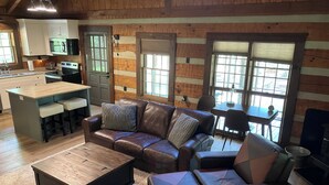 A cozy living room with a leather sofa, a coffee table, and a fireplace. There is a kitchen area with a microwave and a sink. - Well maintained cabin bordering national forest, close to Augusta, GA - -Masters (Edgefield)