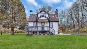 Ein zweistöckiges Haus mit Veranda, Satellitenschüssel und einem Steinsschornstein.
