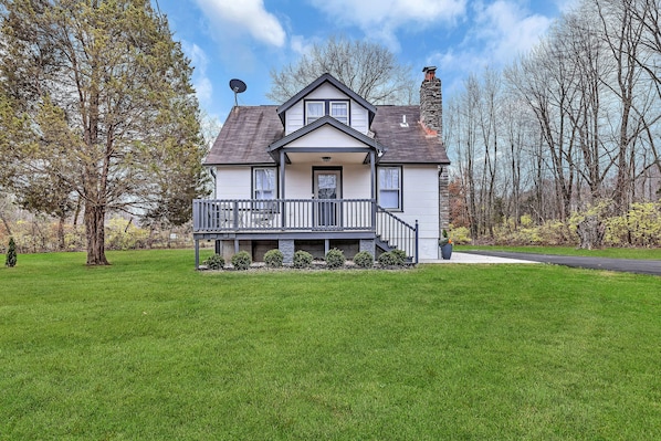 A two-story house with a front porch, a satellite dish, and a stone chimney.