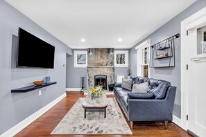 A modern living room with a flat-screen TV, a fireplace, a sofa, and a coffee table.
