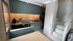 A compact kitchen with teal cabinets, a wooden countertop, and a built-in dishwasher.