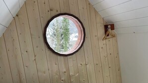 A wooden sloped ceiling with a circular skylight and a wooden hanger.