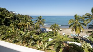 Blick auf einen Strand mit Palmen, sandigem Ufer und Booten.