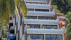Ein mehrstöckiges Gebäude mit Balkonen, einer Treppe und einem geparkten Auto davor.