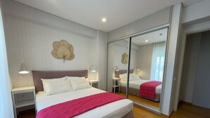 A modern hotel room with a large bed, bedside tables with lamps, a mirror, and a patterned wallpaper. - Athens Riviera 2-Bed Apt & Pool Access #Unoblu® (Alimos)