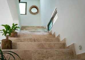 Stunning staircase with potted plants and a circular mirror adorns the wall.