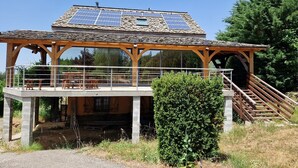 Un edificio con un porche cubierto, paneles solares en el techo y una escalera que lleva a un nivel superior.