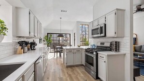 A modern kitchen with white cabinetry, stainless steel appliances, and a large window providing natural light. - 5BR Bonnie Home Steps from It All! (Austin)