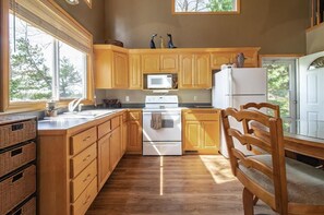 Une cuisine avec des meubles de rangement en bois, un four à micro-ondes, une cuisinière et un réfrigérateur.