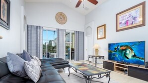 A modern living room with a black leather sofa, a coffee table, and a flat-screen TV. - Modern 5 bed villa on gated community, 20 minutes from Disney (Davenport)