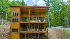 Una cabaña de madera de varios pisos con balcones, una escalera y suelo de tierra.