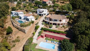 Vista aérea de uma área residencial com várias casas, uma piscina e um gramado bem cuidado.